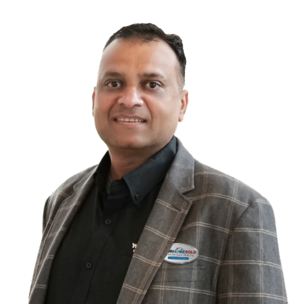 Sharad Gupta; Sharad Gupta, dressed in a professional plaid blazer and black shirt, with a 'Your Home Sold Guaranteed Realty' badge, smiles confidently.